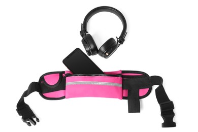 Stylish pink waist bag with smartphone and headphones on white background, top view