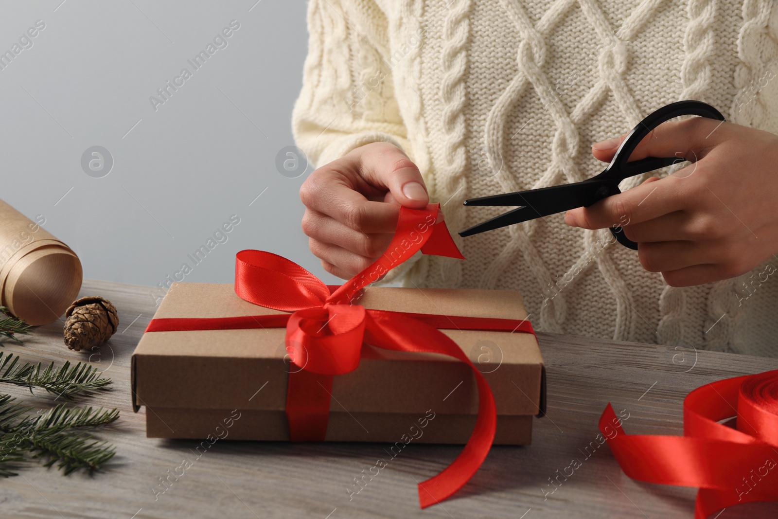 Photo of Woman decorating gift box at wooden table, closeup. Christmas present
