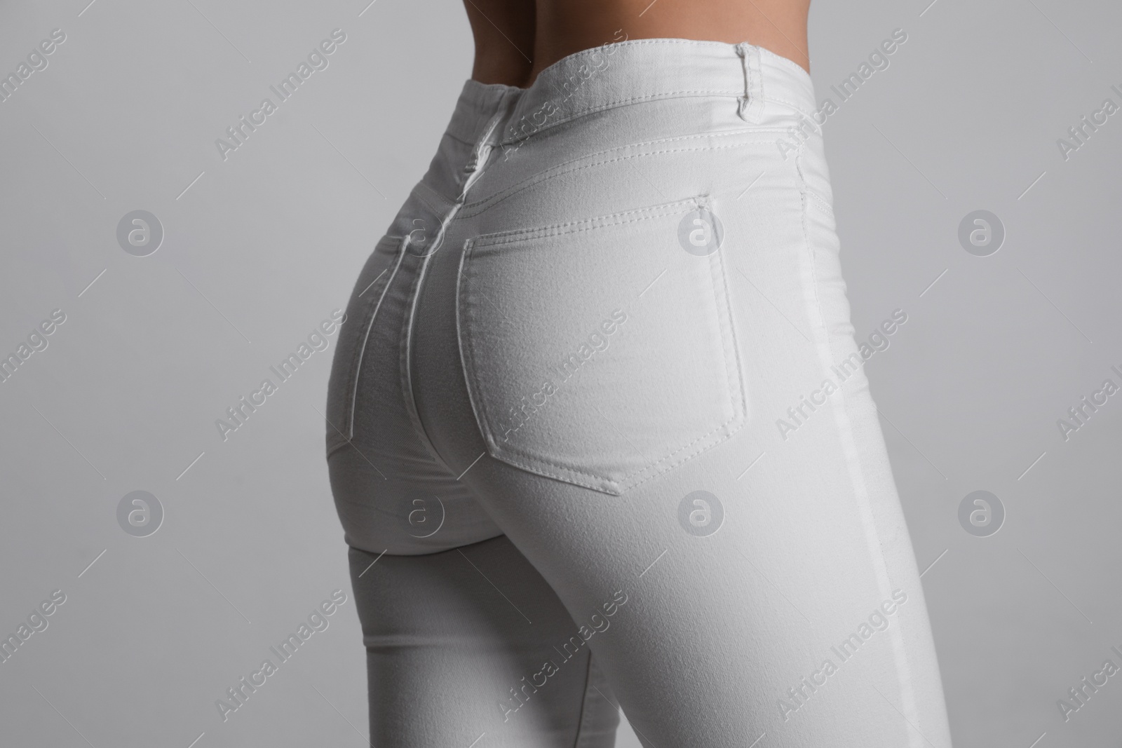 Photo of Woman in stylish white jeans on light background, closeup