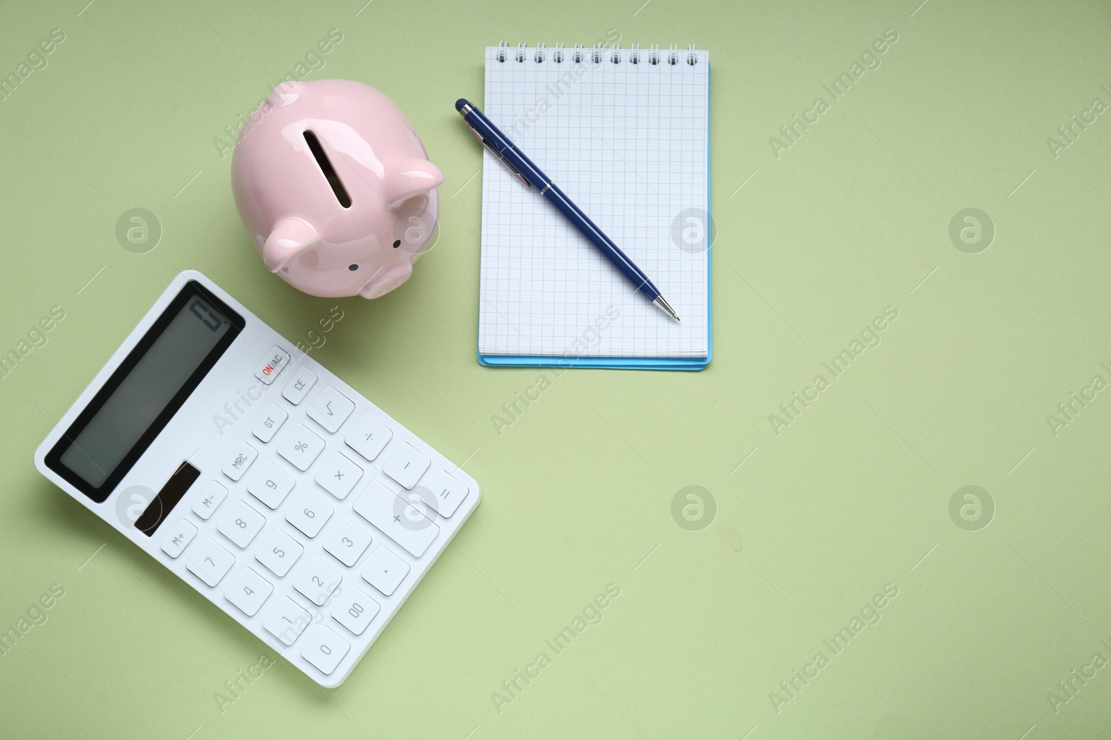 Photo of Piggy bank, notebook and calculator on light green background, flat lay. Space for text
