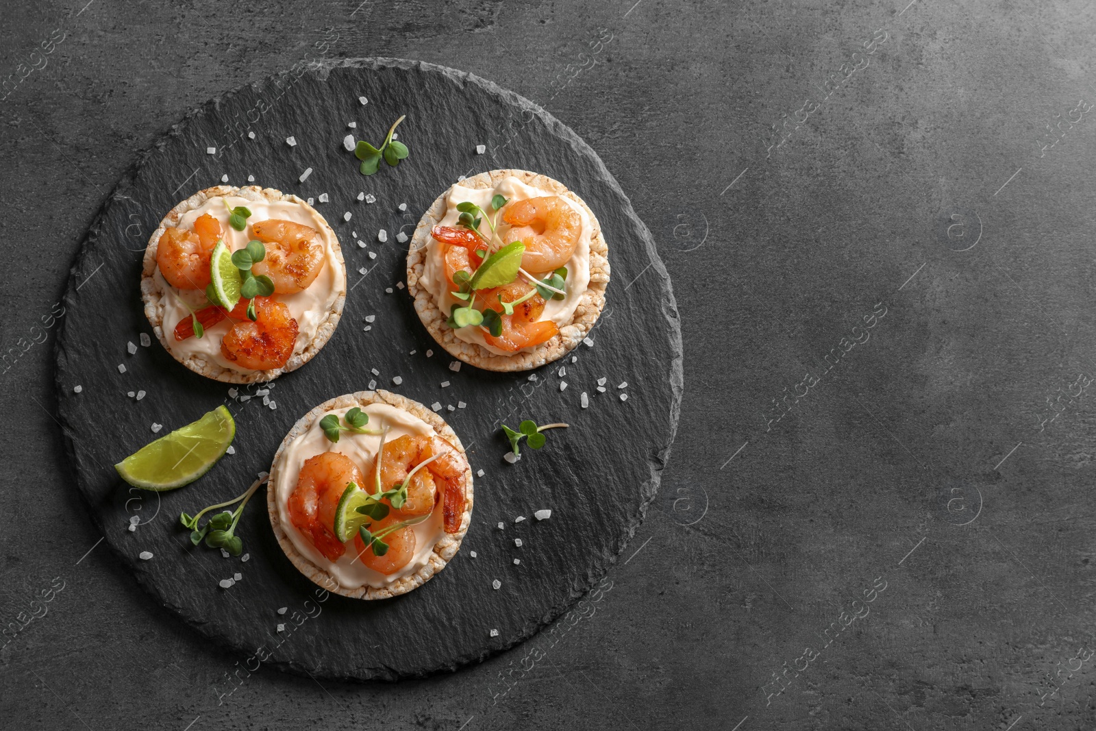 Photo of Delicious small sandwiches with shrimps on slate plate