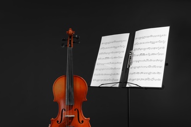 Photo of Violin and note stand with music sheets on black background