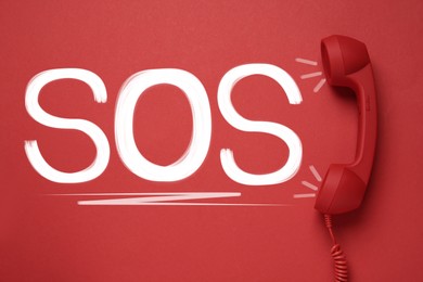Image of Telephone handset on red background, top view. Emergency SOS call