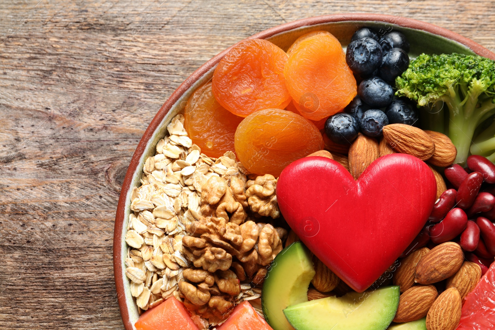 Photo of Plate with heart-healthy products on wooden background, top view