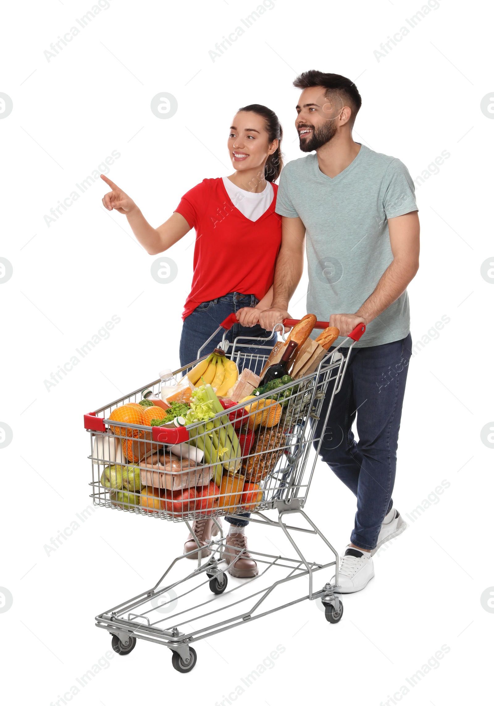 Photo of Happy couple with shopping cart full of groceries on white background