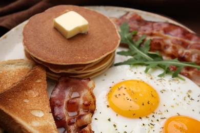 Photo of Tasty pancakes with fried eggs and bacon on plate, closeup