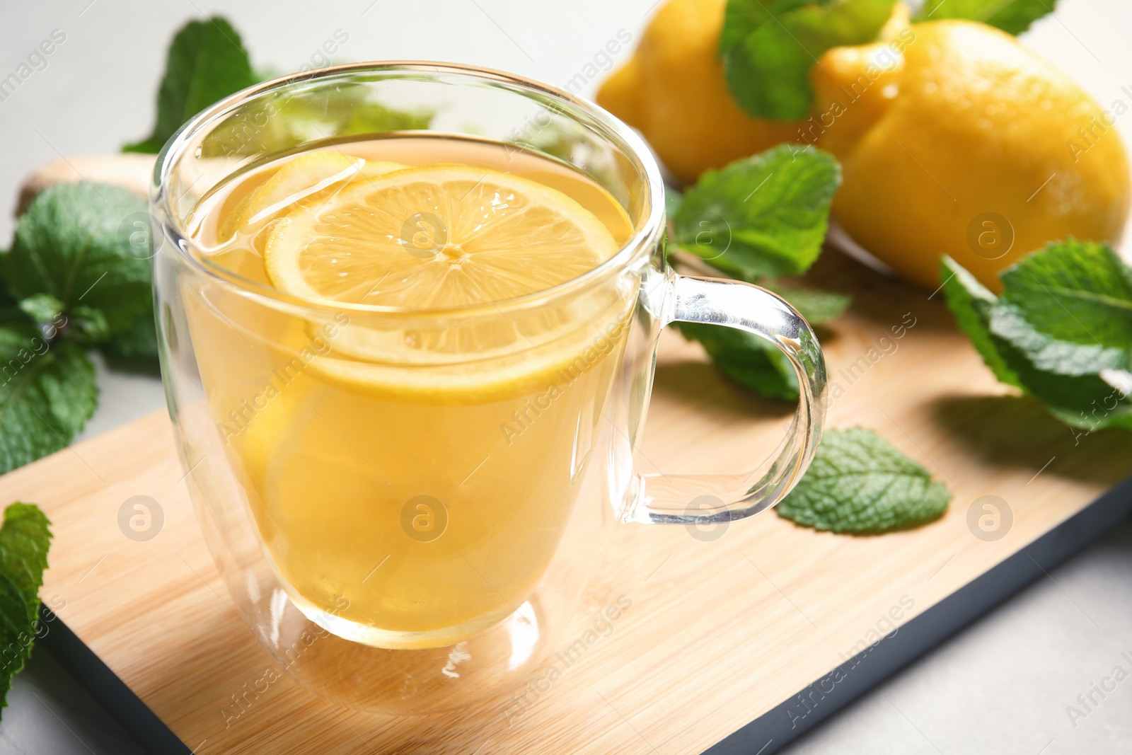 Photo of Glass cup with hot tea and lemon on table