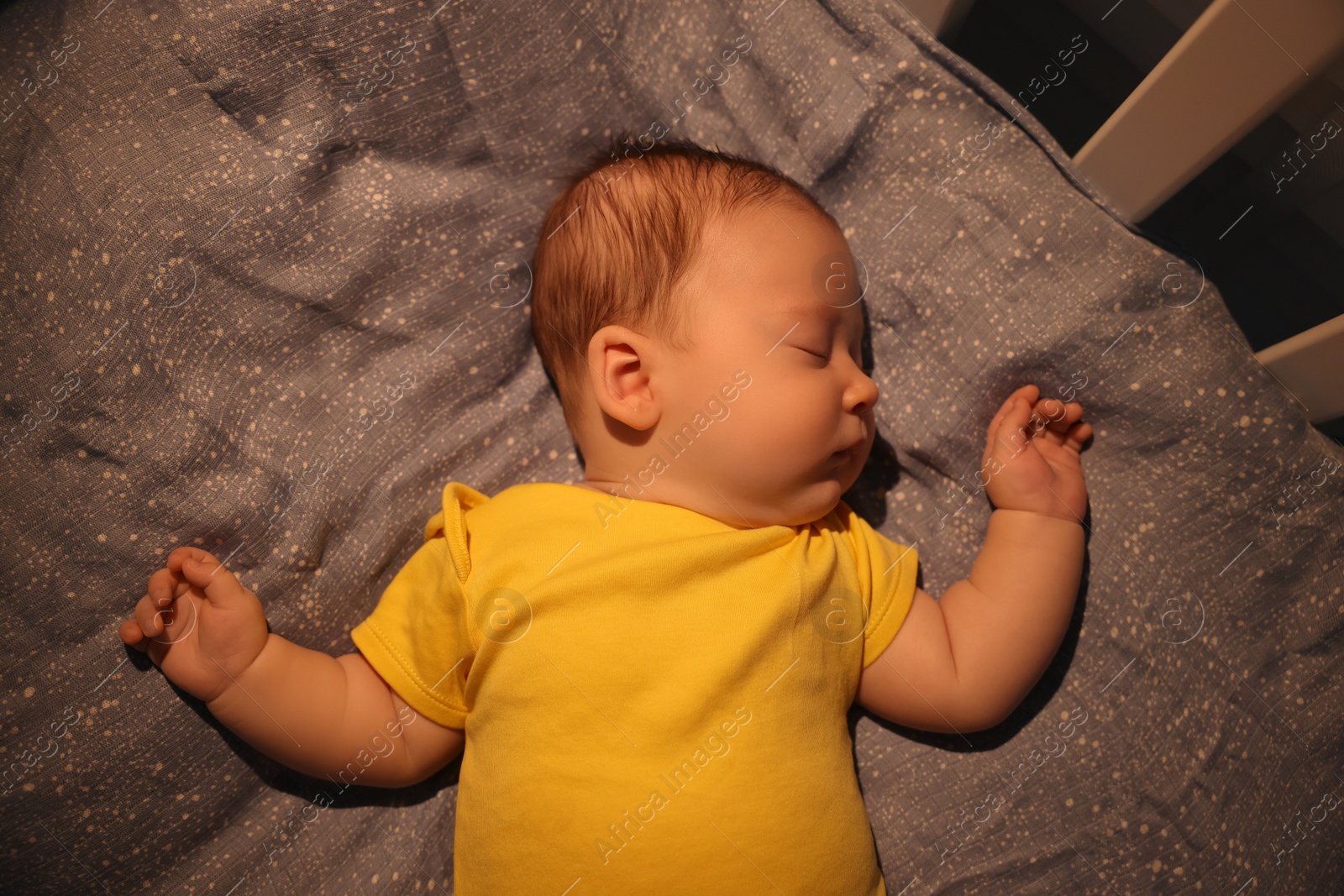 Photo of Cute newborn baby sleeping in crib at night, top view