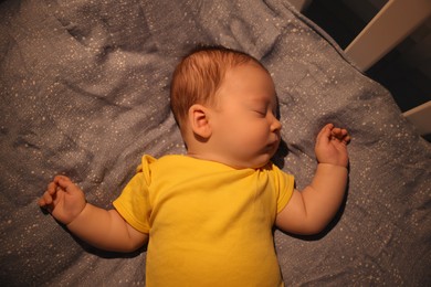 Cute newborn baby sleeping in crib at night, top view