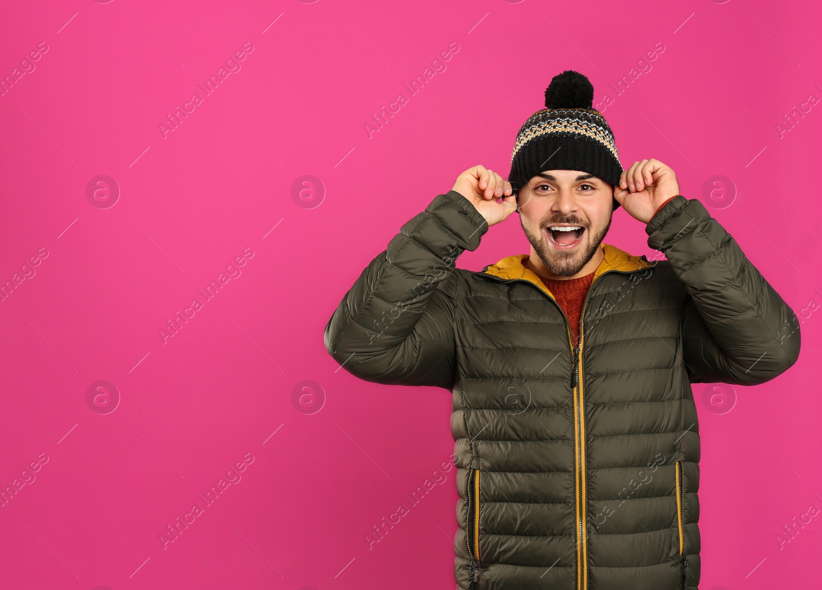 Photo of Happy young man in warm clothes on pink background, space for text. Winter vacation