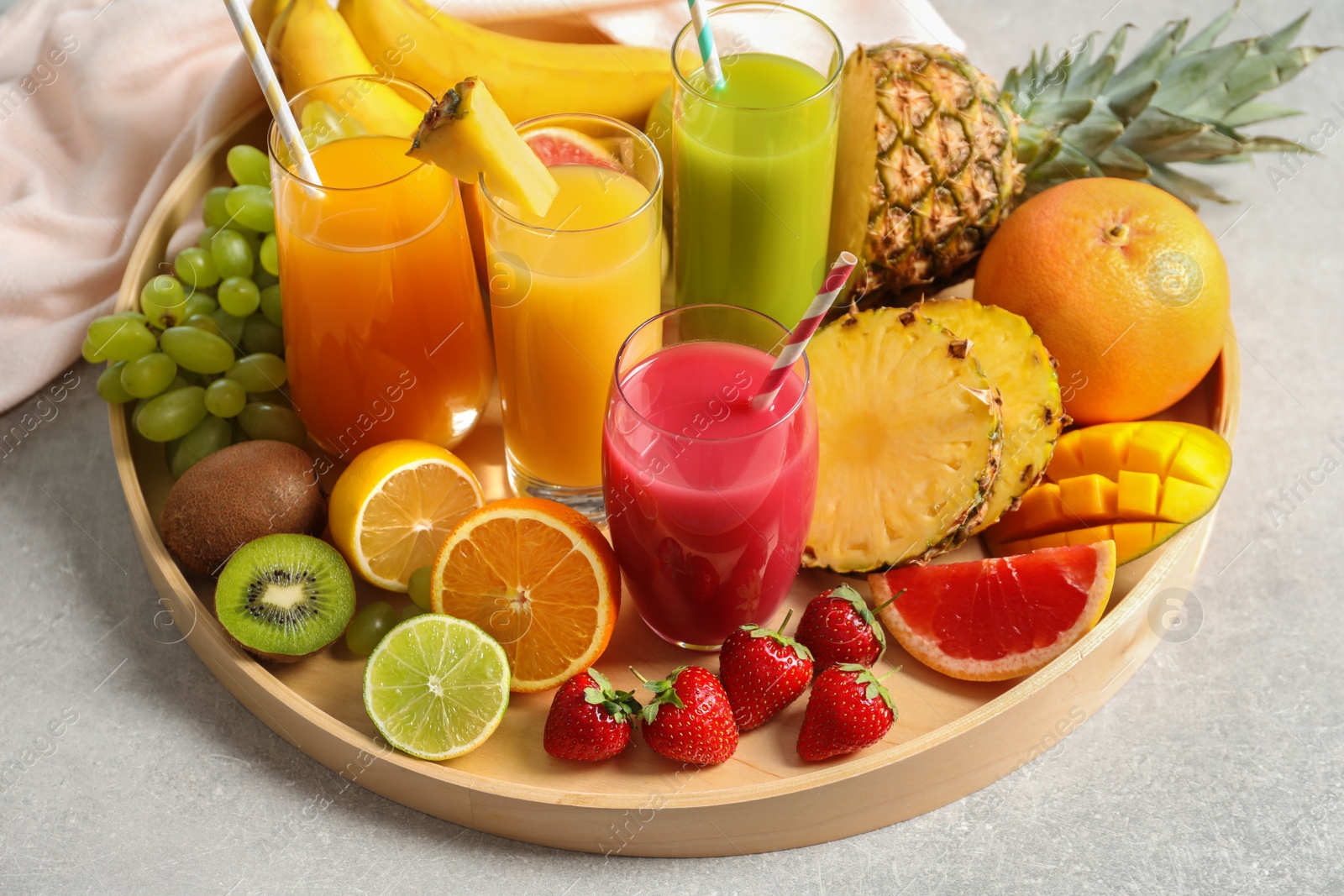 Photo of Wooden tray with glasses of different juices and fresh fruits on table