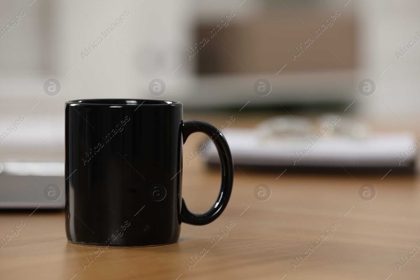 Photo of Black ceramic mug on wooden table at workplace. Space for text