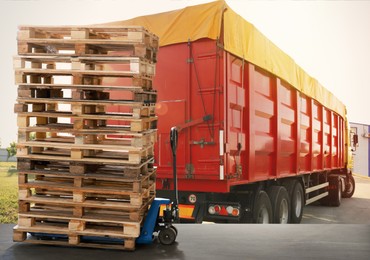 Image of Modern manual forklift with wooden pallets near truck outdoors on sunny day