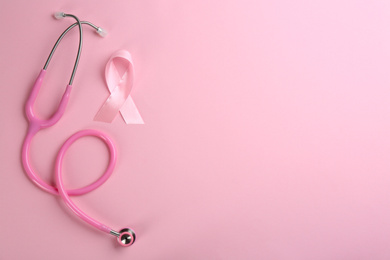 Photo of Pink ribbon as breast cancer awareness symbol and stethoscope on color background, flat lay. Space for text