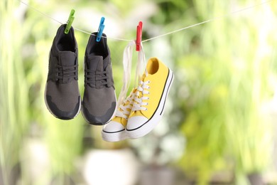 Different stylish sneakers drying on washing line against blurred background