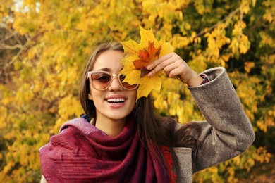 Photo of Young beautiful woman with leaves in park. Autumn walk