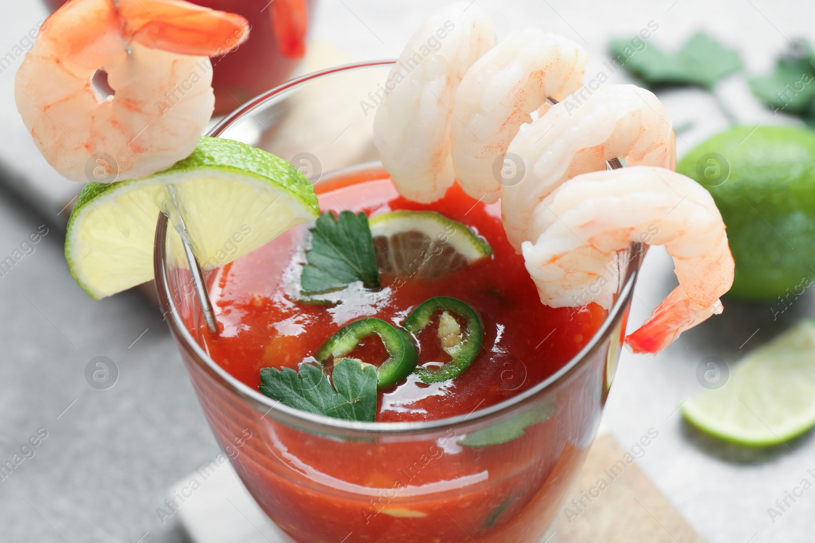 Photo of Tasty shrimp cocktail with sauce in glasses and lime on light table, closeup