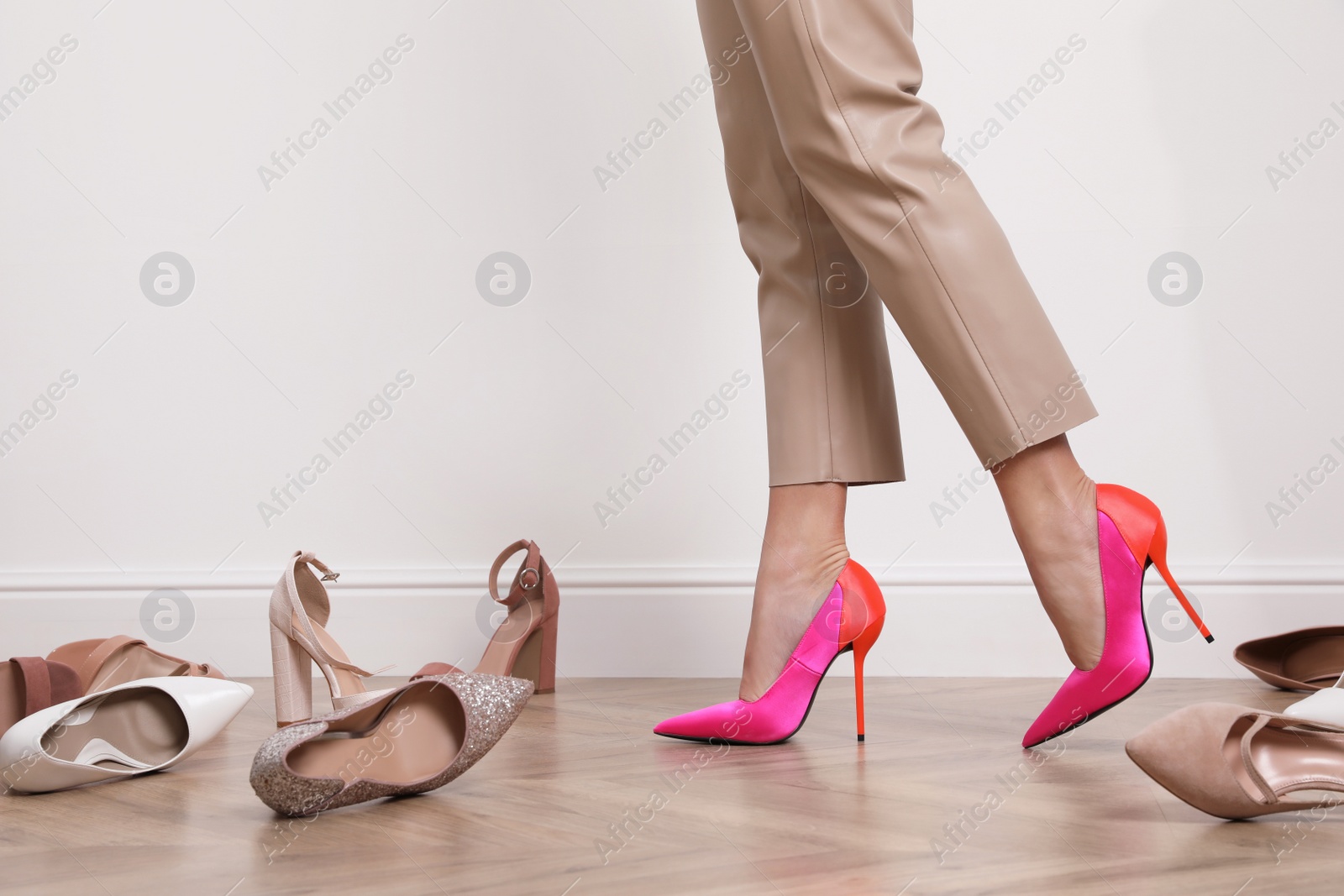 Photo of Woman trying on different shoes indoors, closeup