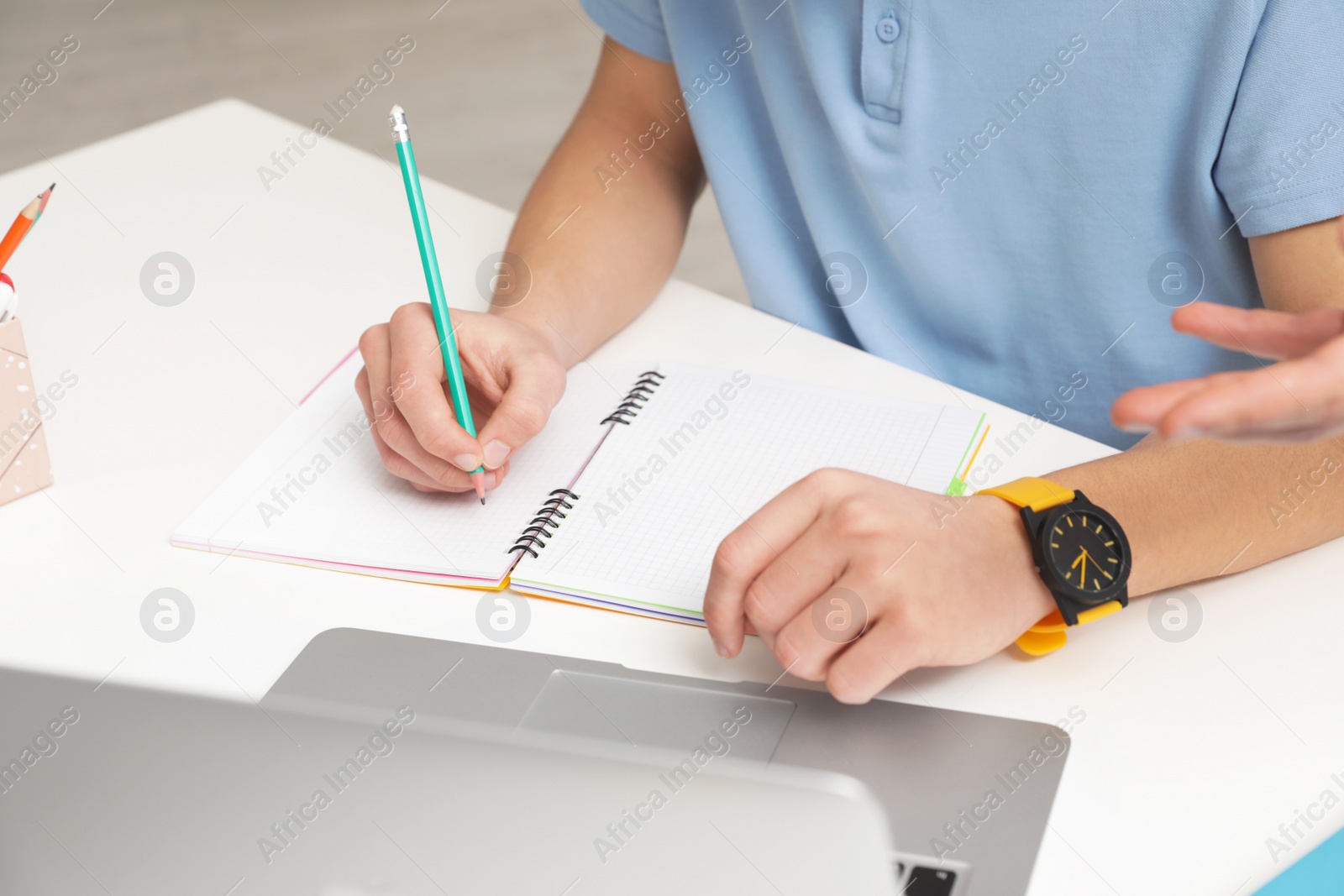 Photo of Teenager boy doing his homework at desk, closeup