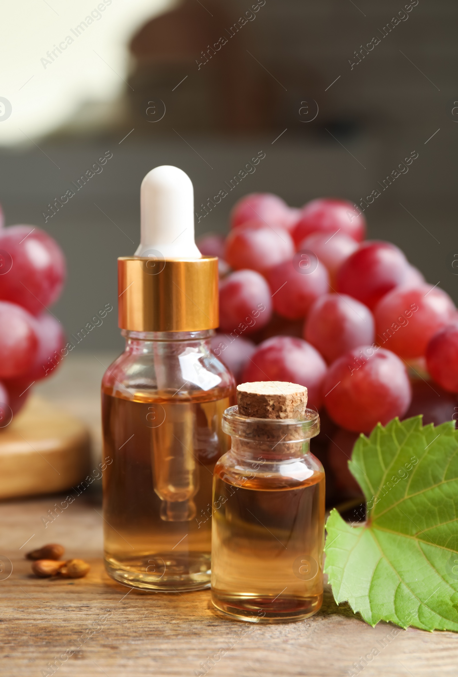 Photo of Natural grape seed oil and fresh berries on wooden table. Organic cosmetic