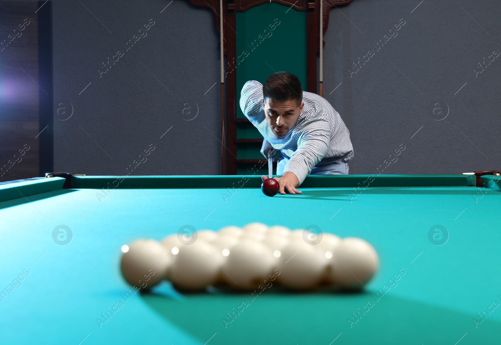 Photo of Handsome young man playing Russian billiard indoors