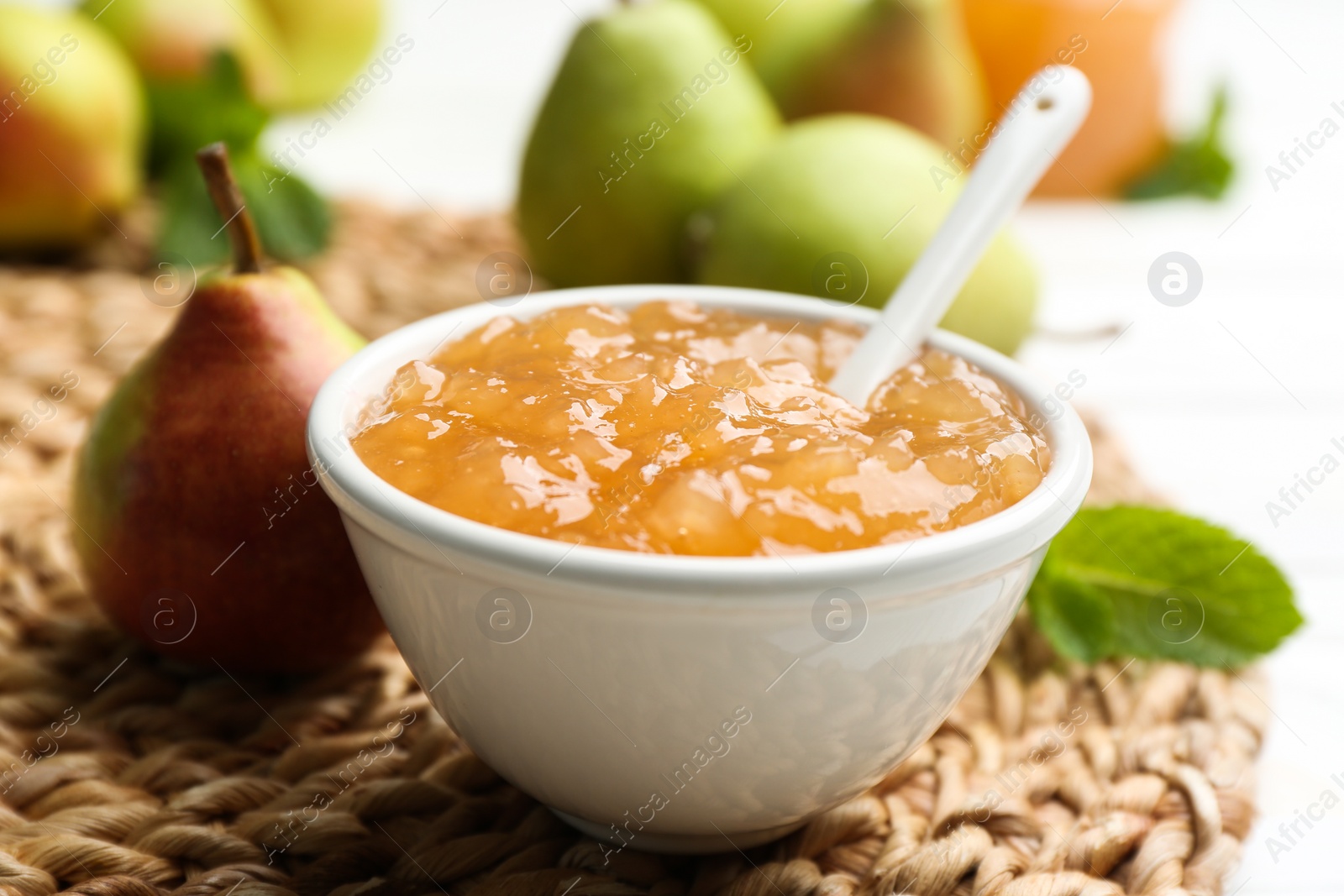 Photo of Delicious pear jam on wicker mat, closeup