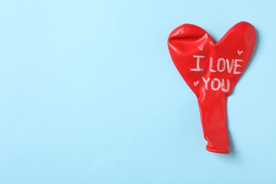 Heart shaped balloon with phrase I Love You on light blue background, top view