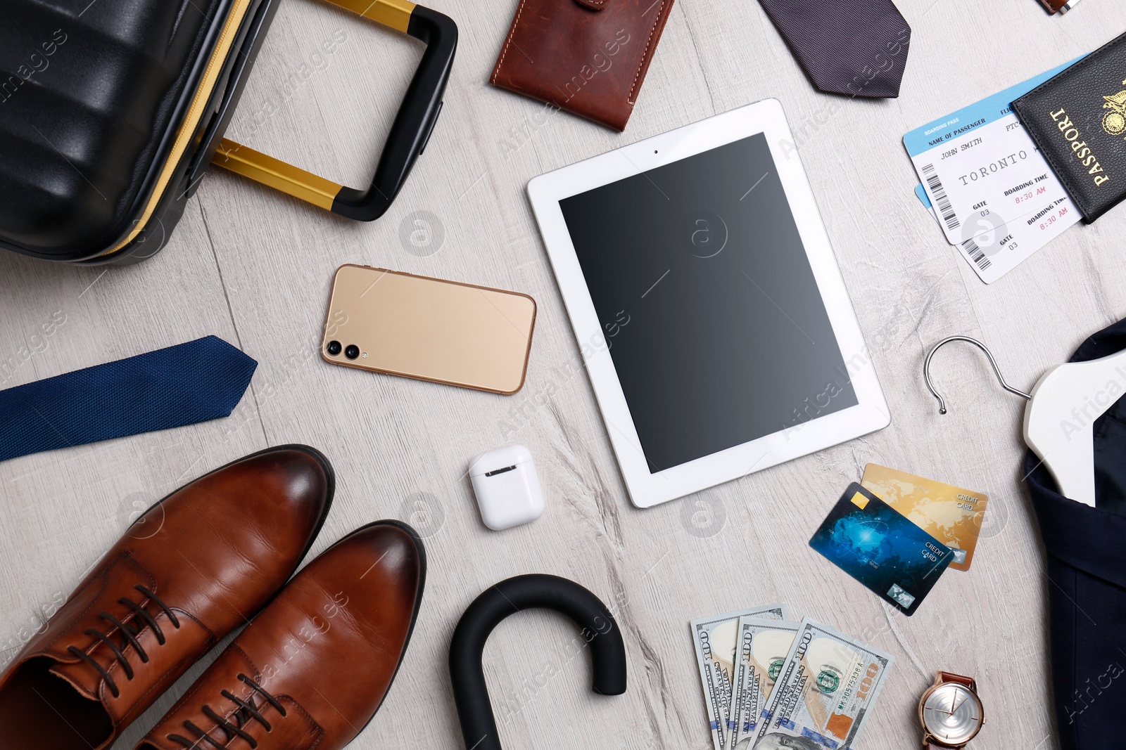 Photo of Business trip stuff and suitcase on light wooden surface, flat lay