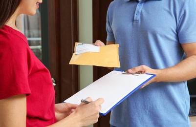 Photo of Woman receiving padded envelope from delivery service courier indoors, closeup