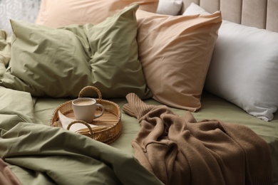 Photo of Cup of hot coffee on bed with pistachio linen in room