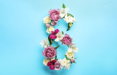 Number 8 made of beautiful flowers on light blue background, flat lay. International Women's day