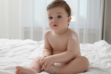 Photo of Cute little baby with cream on arm indoors