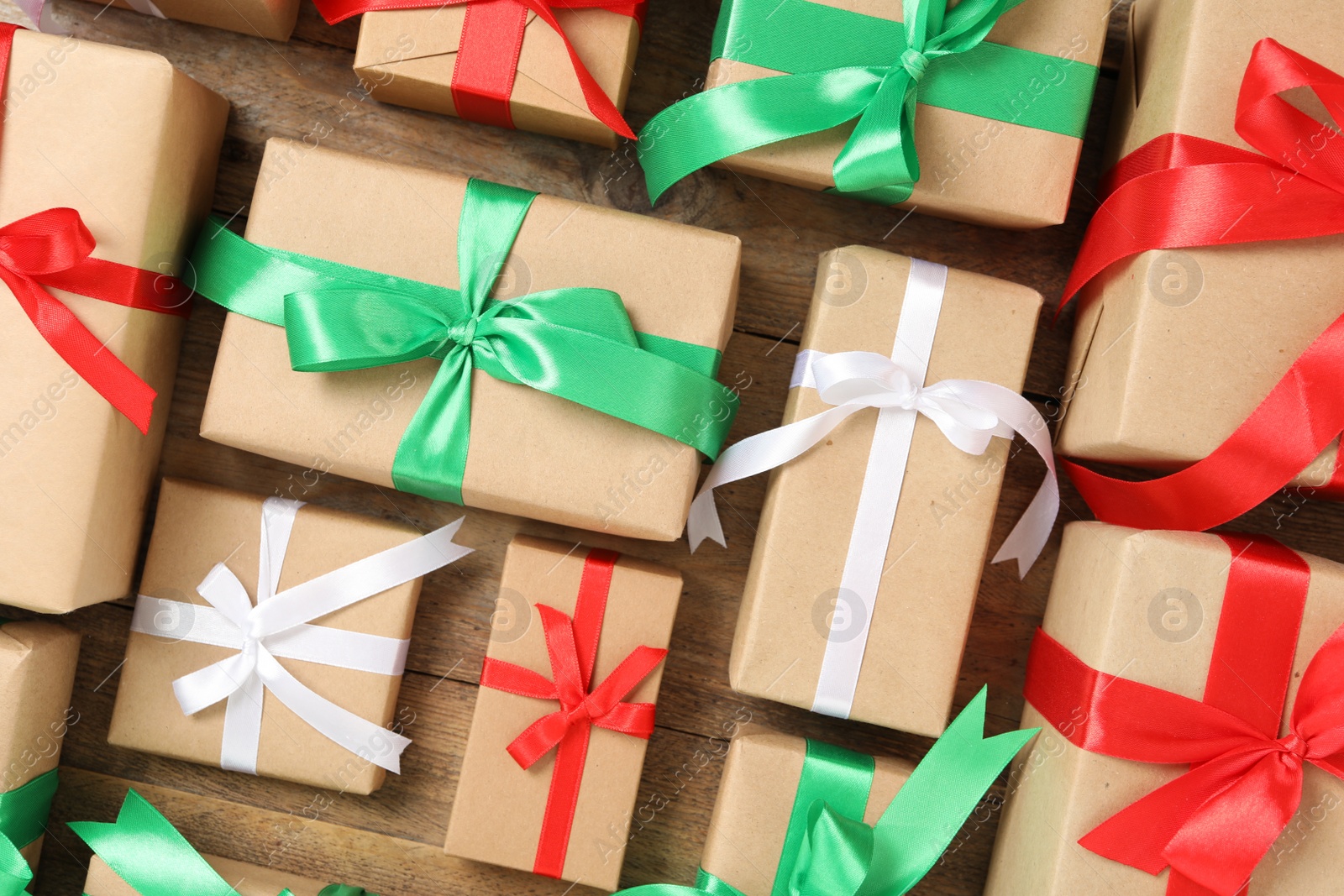 Photo of Christmas gift boxes with bows on wooden background, flat lay