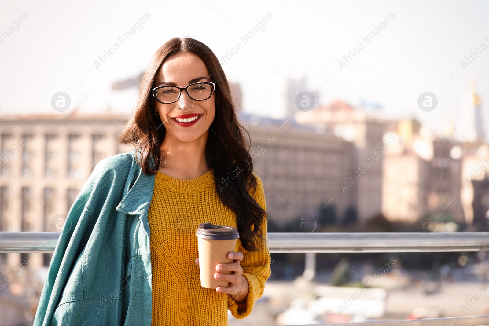 Photo of Beautiful woman with cup of coffee on city street. Autumn walk