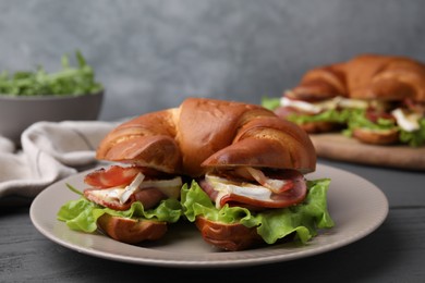 Photo of Tasty crescent roll with brie cheese, ham and bacon on grey table, closeup