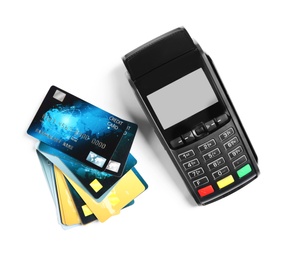 Modern payment terminal and credit cards on white background, top view