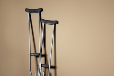 Pair of axillary crutches on beige background. Space for text