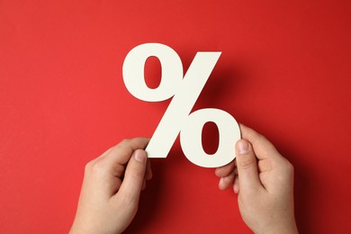 Photo of Man holding percent sign on red background, top view