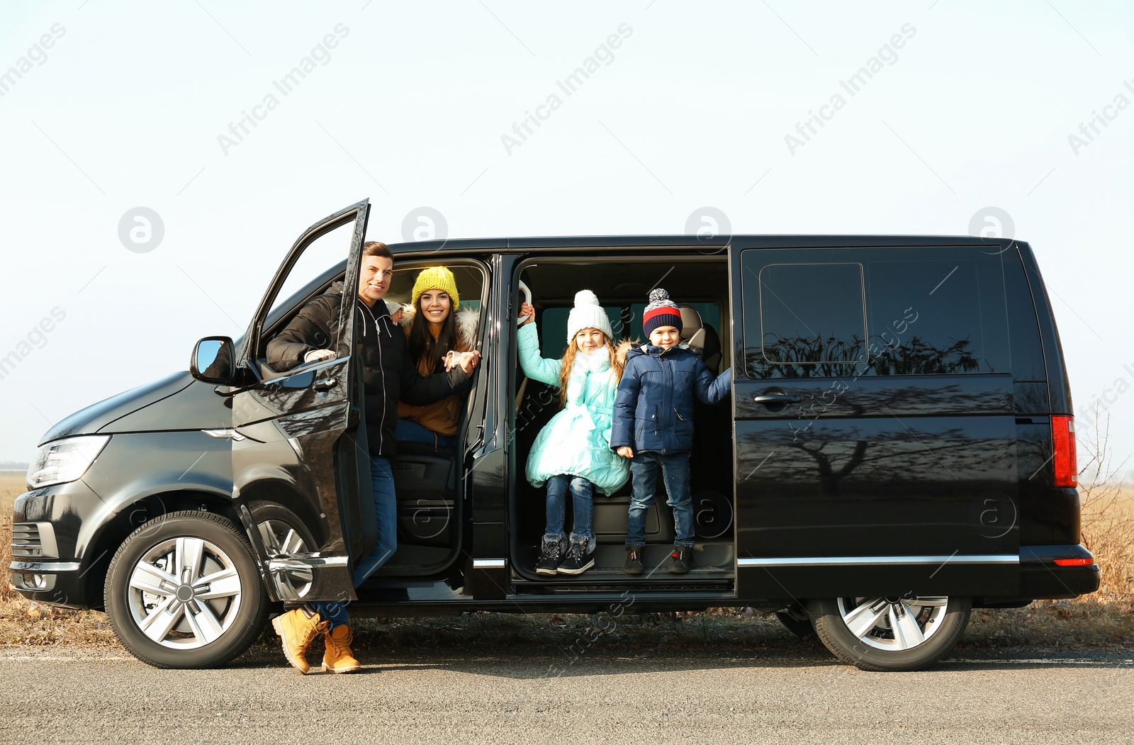 Photo of Happy family with little children in modern car on road