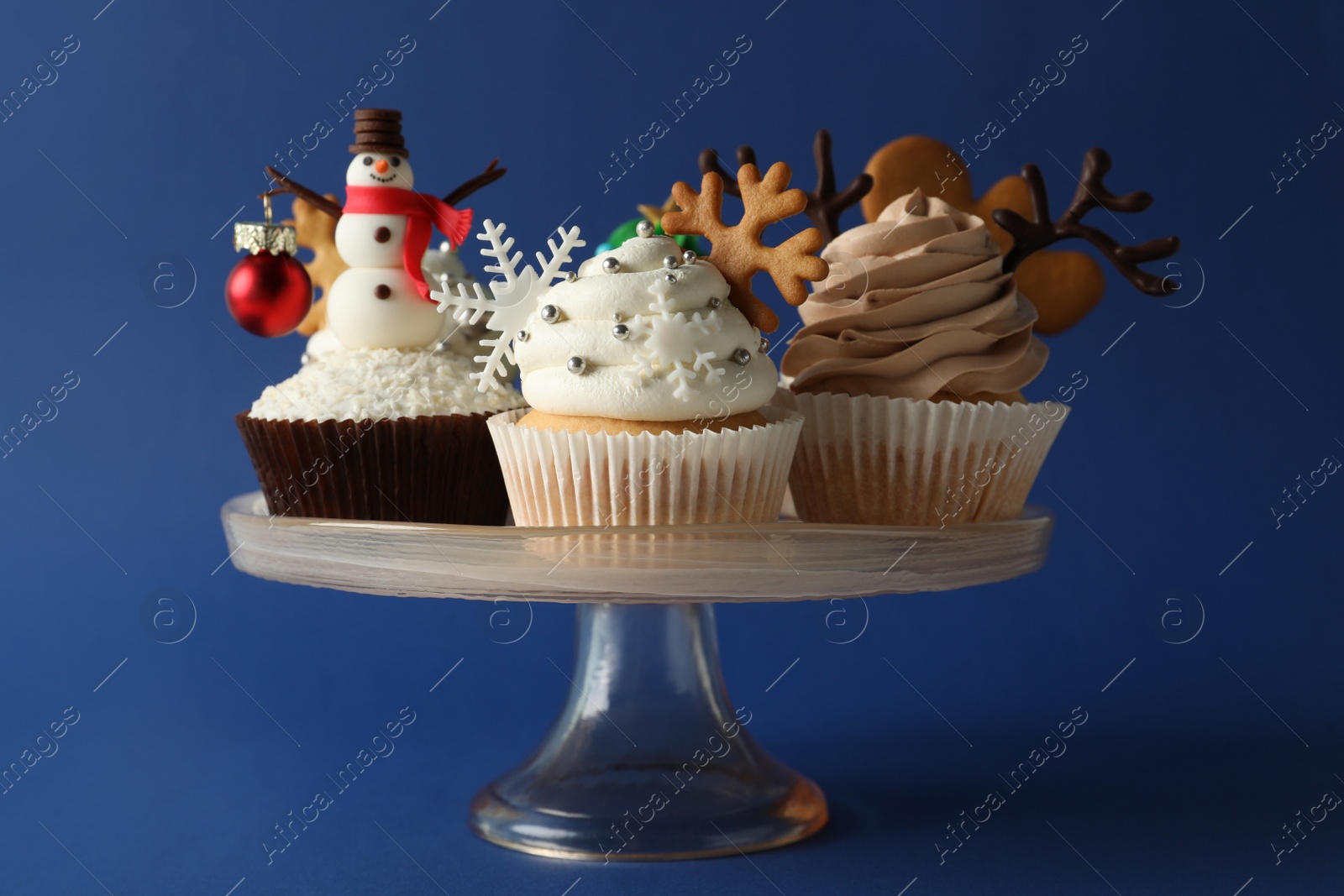 Photo of Dessert stand with tasty Christmas cupcakes on blue background