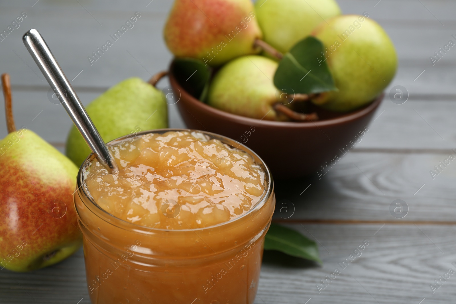 Photo of Delicious pear jam and fresh fruits on grey table, closeup