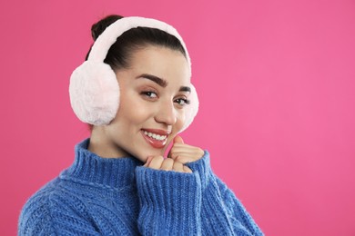 Photo of Beautiful young woman wearing earmuffs on pink background. Space for text