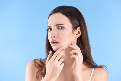 Teenage girl with acne problem against color background