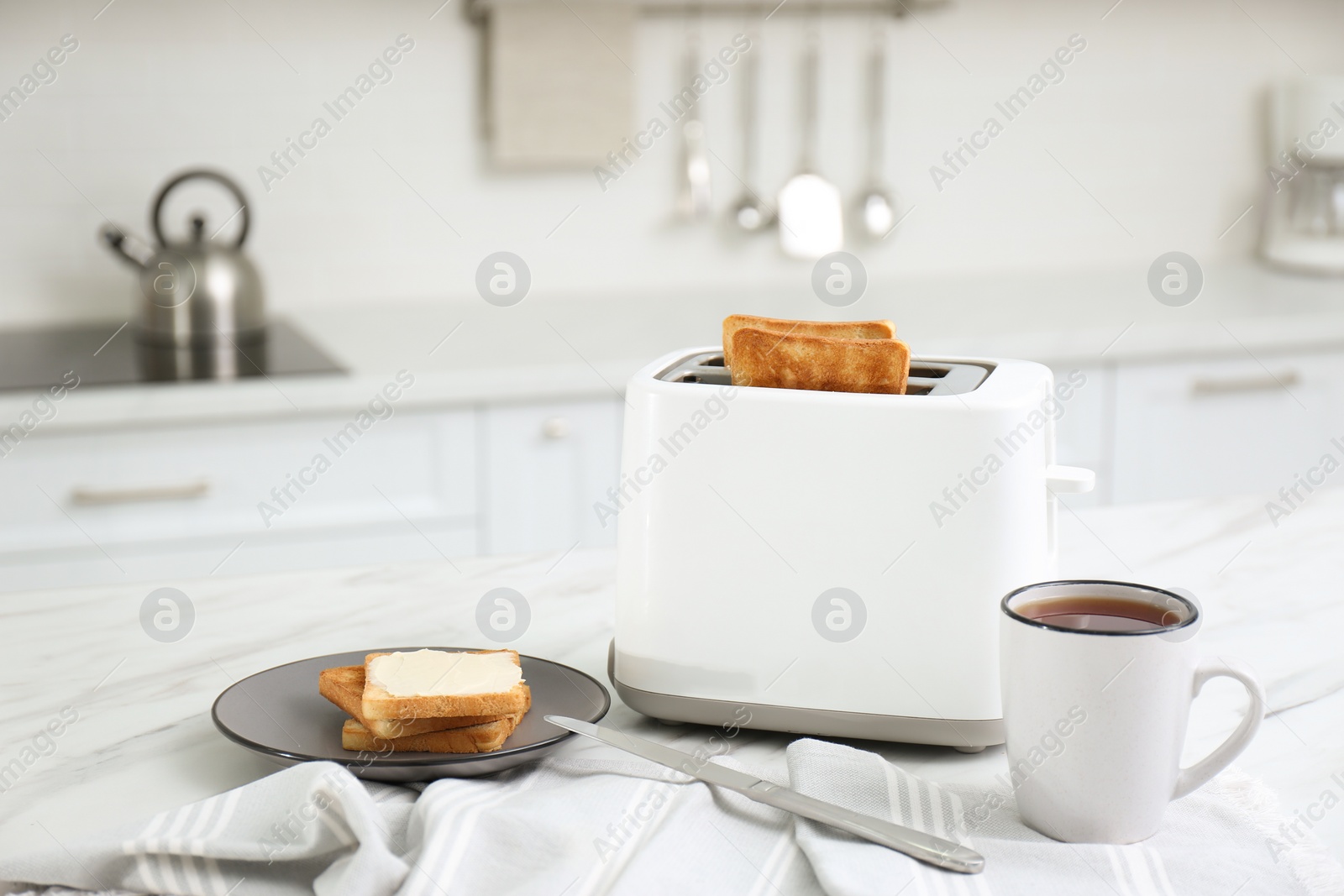 Photo of Modern toaster and tasty breakfast on white marble table in kitchen