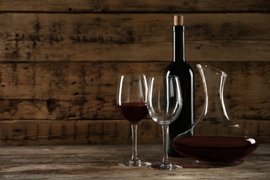 Glassware and bottle with red wine on wooden table