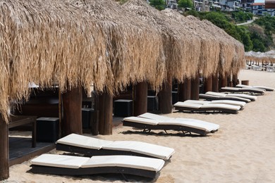 Photo of Beautiful straw umbrellas and sunbeds on sandy beach