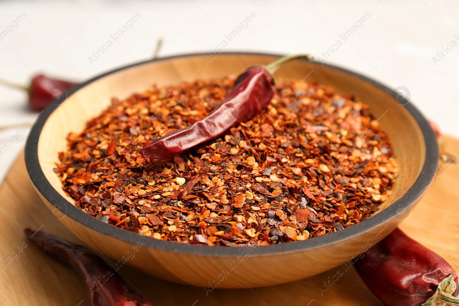 Photo of Bowl with crushed chili pepper and pods, closeup