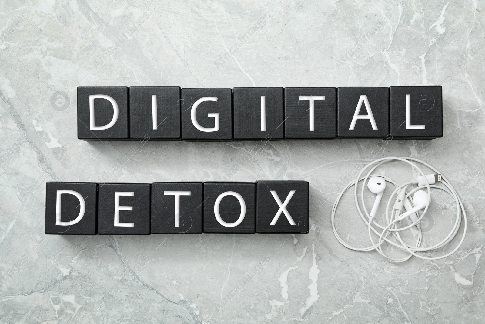 Photo of Black cubes with words DIGITAL DETOX and earphones on light grey marble background, flat lay