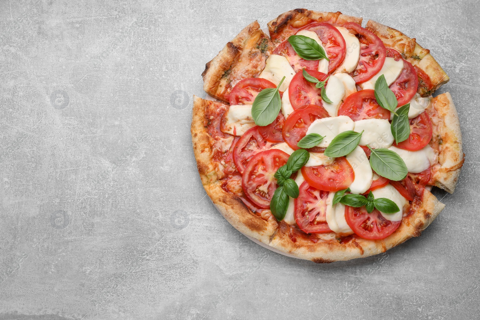 Photo of Delicious Caprese pizza with tomatoes, mozzarella and basil on light grey table, top view. Space for text