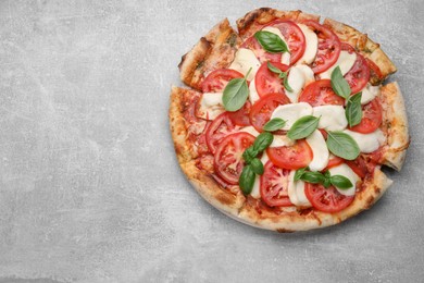 Delicious Caprese pizza with tomatoes, mozzarella and basil on light grey table, top view. Space for text